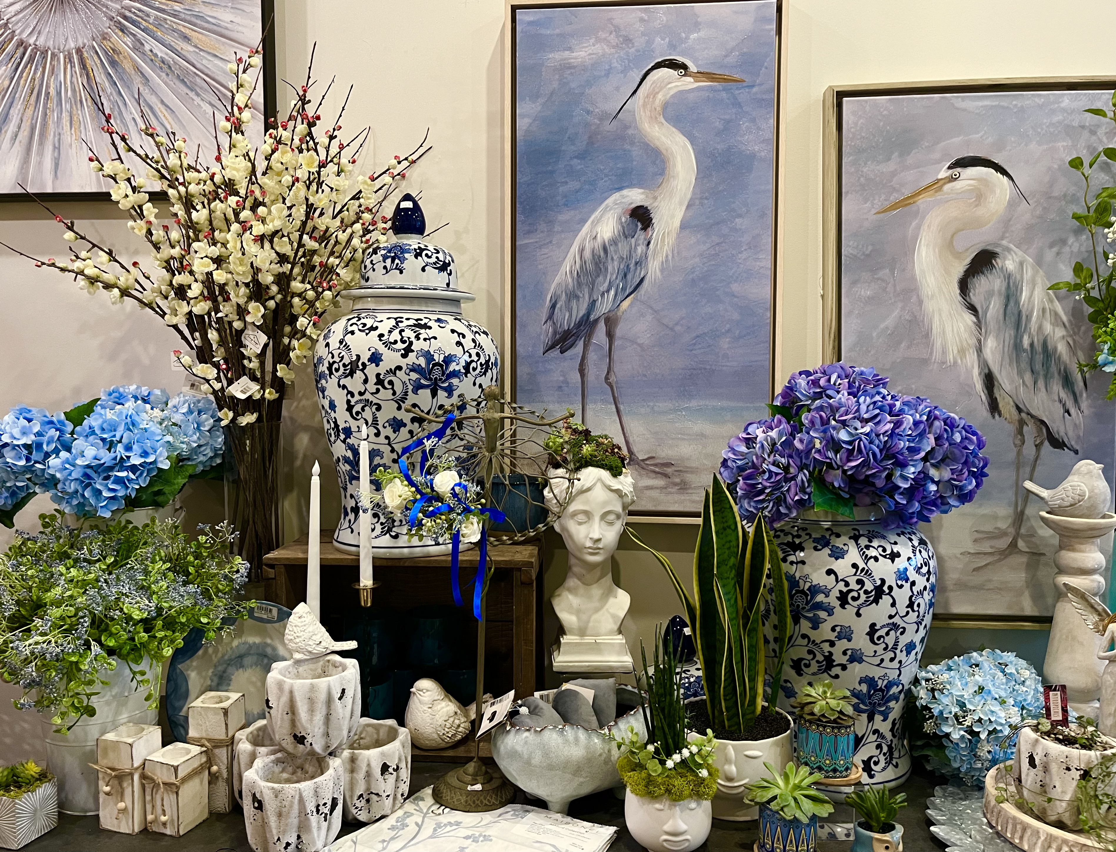 A blue and white display with painted herons, hydrangeas, and patterned ceramic vases