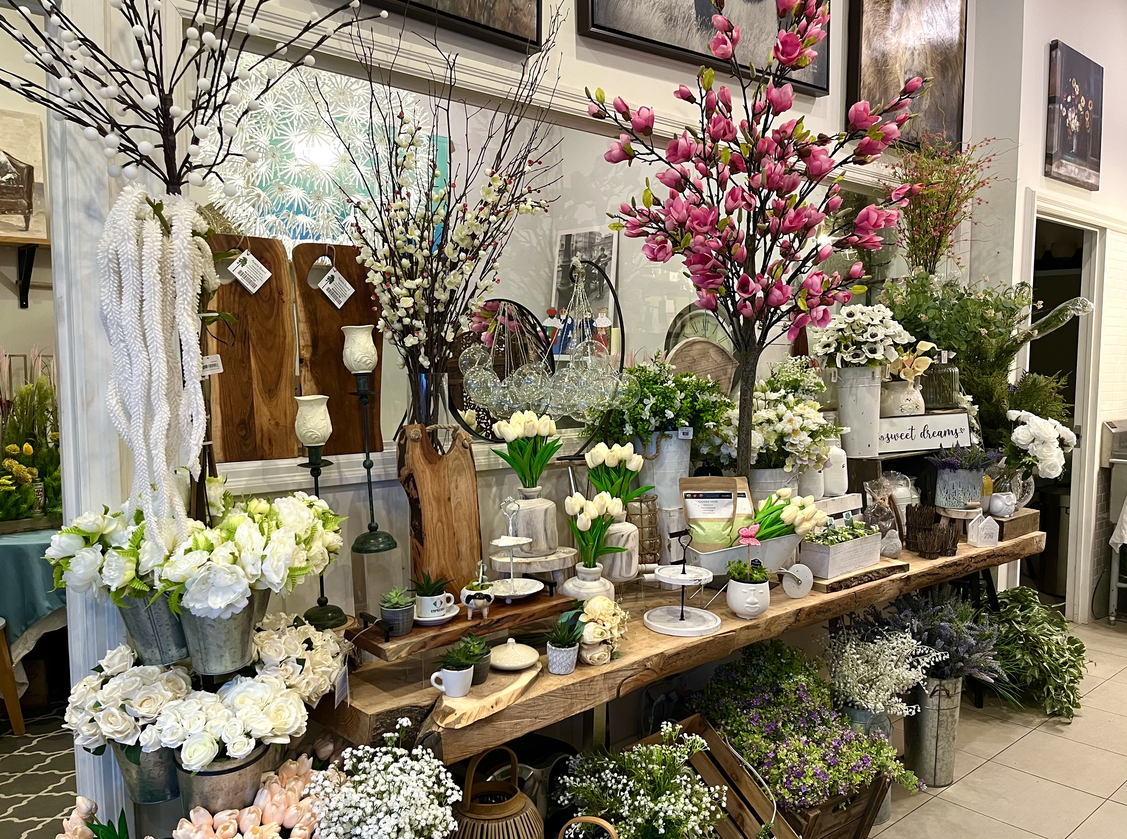 A rustic wooden display with pale tulips, cherry blossoms, and zinc buckets